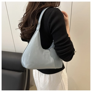 Side view of light blue patent leather hobo bag worn on shoulder by a model
