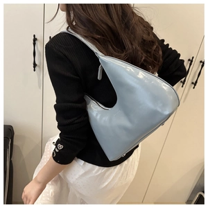 Close-up of light blue patent leather crescent bag with top zipper and glossy finish
