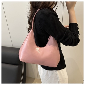 Detail of pink patent leather hobo bag worn on shoulder showing glossy texture and fashion logo