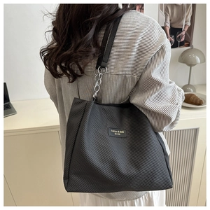 Detail of black tote bag with diagonal embossed texture and chain leather shoulder strap
