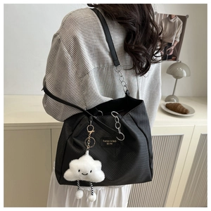 Close-up of black woven tote bag with silver chain and white cloud plush charm