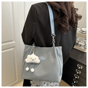 Blue corduroy tote bag with cloud charm shown on model in a high-quality fashion setting
