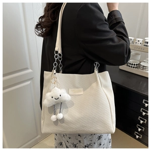 Detail of white textured canvas tote bag with leather strap and plush cloud charm
