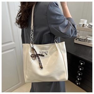 Detail of white PU leather tote with silver bow and woven racket pendant on shoulder