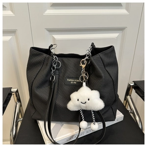 Détail d'un cabas noir tissé avec chaîne argentée et breloque nuage en peluche