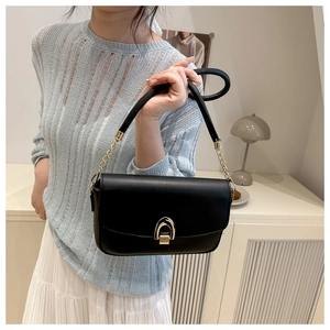 Close-up of black leather crossbody bag with golden horseshoe metal buckle and chain strap