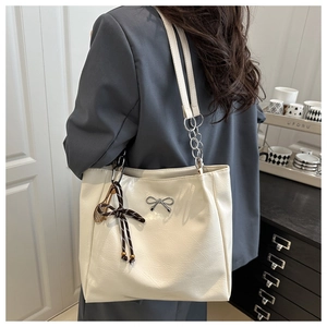 Detail of cream tote bag with silver bow hardware and black and white rope tassel
