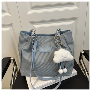 Détail du sac cabas bleu tissé avec poignée en chaîne argentée et breloque nuage blanc