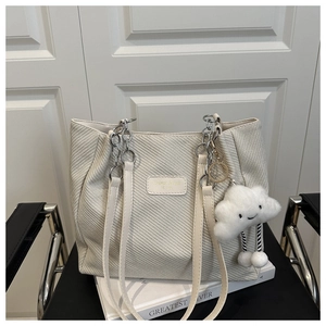 Détail du cabas tissé blanc cassé avec bandoulière chaîne et charme nuage peluche