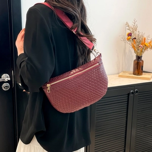 Burgundy woven shoulder bag with pink wide strap worn by a model in a modern home setting