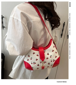 Detail of red cherry print and vibrant red leather trim on retro shoulder bag strap