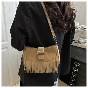 Détails d'un sac besace en daim marron avec franges vintage et boucle métallique à l'épaule