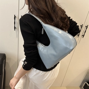 Light blue glossy leather crescent shoulder bag with patent finish shown on model