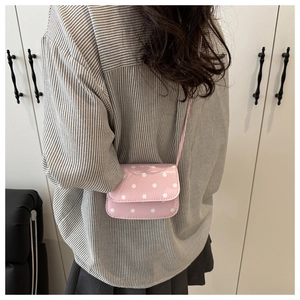 Rear view of a model wearing a pink polka dot mini shoulder bag with slim strap