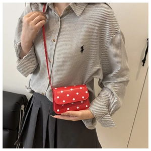 Red retro polka dot shoulder bag shown styled on a model in a casual indoor setting