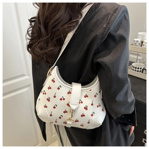 Close-up of white shoulder bag with red cherry prints and golden metallic buckle detail