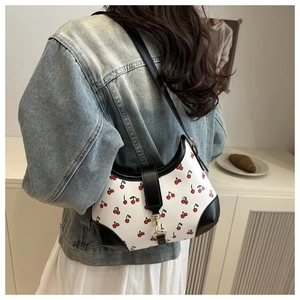 Detail of cherry print shoulder bag with black leather trim and gold metal buckle