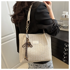 Dettaglio della borsa tote in paglia beige con trama a V e catena in metallo elegante