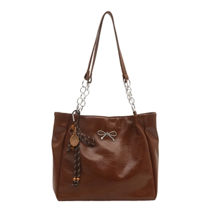 Brown oil wax faux leather tote bag with tennis racket charm and metal bow detail