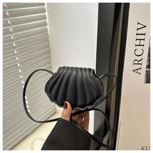 Detail of a mini black shell-shaped crossbody bag with quilted faux leather texture