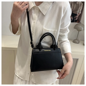 Detail of black leather handbag with gold Fashion Bag lettering and metal hardware