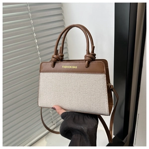 Detail of brown leather and beige canvas tote bag with fashion text and knotted handles