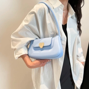 Borsa sottobraccio azzurra minimalista con fibbia a cuore dorata su modella