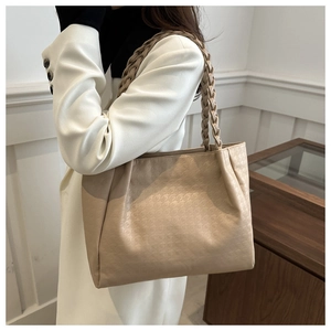 Dettaglio della borsa beige con trama pied de poule e manici intrecciati chic
