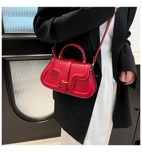 Modella che indossa una borsa a sella in pelle rossa martellata con fibbia dorata e cuciture