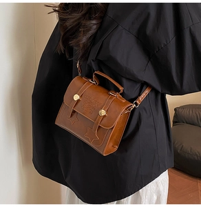 Detail of vintage brown leather handbag featuring golden buckles and star patch accents