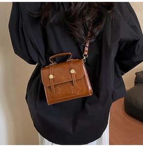 Detail of vintage brown textured leather satchel with star motifs and gold lock hardware