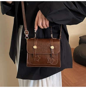 Detail of vintage brown PU leather handbag featuring star patch and letter embossing