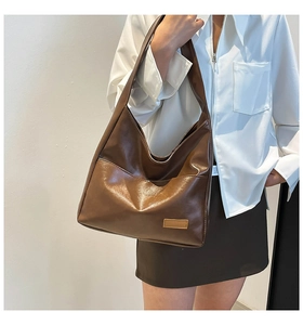 Detail of a large capacity brown tote bag showing smooth leather texture and shoulder strap