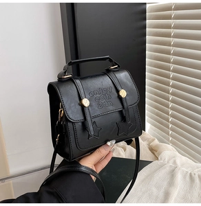 Detail of black PU leather square bag with star embossing and gold hardware