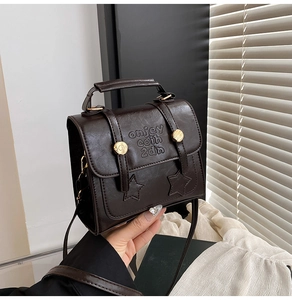 Detailed close-up of dark brown leather texture and vintage gold buckle on messenger bag