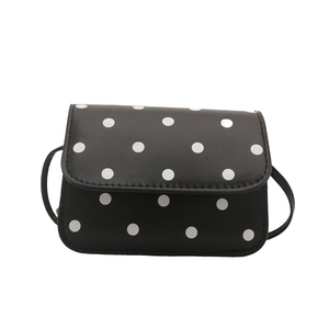 Chic mini black shoulder bag with white polka dots and leather strap on white background