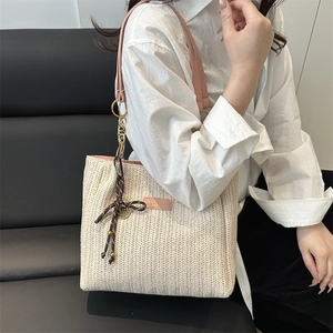 Beige woven bucket tote bag with pink leather straps and decorative tassel for summer