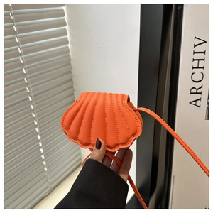 Close-up of orange shell-shaped mini crossbody bag with pleated synthetic leather detail