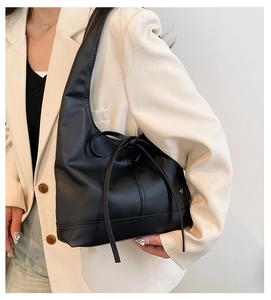 Detail of elegant black tote bag featuring a chic bow strap for commuting style
