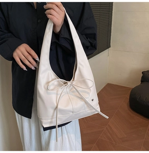 Detailed view of the large bow accent on this elegant cream white tote bag's front