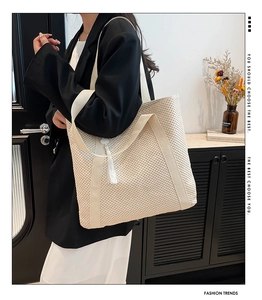 Detail of a cream woven tote bag with fringe tassels and wide shoulder strap style