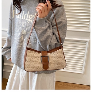 Detail of hand-woven straw shoulder bag with brown leather trim and silver buckle clasp