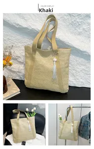 Detailed shot of khaki straw tote bag featuring elegant white tassel and woven handles