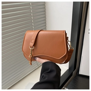 Close-up of brown textured leather bag featuring a gold clasp and decorative metal chain