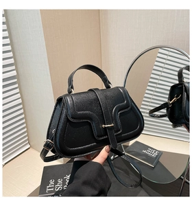 Detailed view of black litchi pattern leather texture and gold buckle on flap bag
