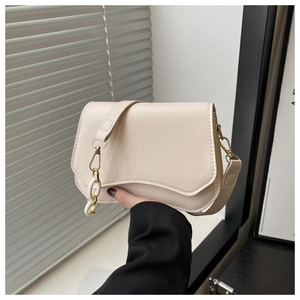 Detail of cream white leather bag with unique wavy flap and golden metal hardware