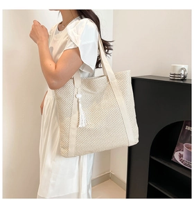 Detailed macro view of the dense woven texture and white fringe tassel on a beige tote bag