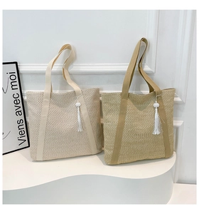 Detailed close-up of woven straw tote bags in beige and khaki with white fringe tassel