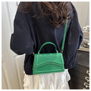 Detail of green square handbag with wavy stitching and detachable strap on white skirt