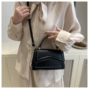 Gros plan d'un sac bandoulière noir avec coutures ondulées et détails dorés
